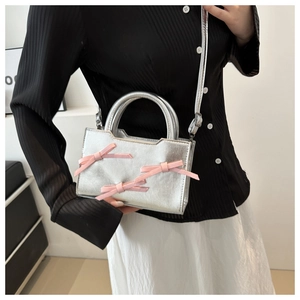 Model view of silver metallic bag with pink bows, showing hand-held and crossbody style