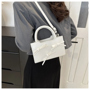 Close-up of white PU leather handbag featuring three stylish decorative bow details