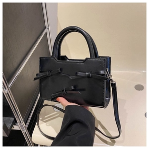 Vue détaillée du sac à main noir avec trois nœuds et bandoulière amovible