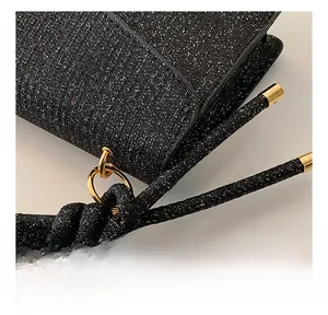 Detail of black glitter fabric with premium gold ring hardware and knotted strap accents