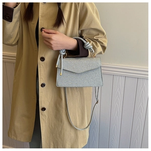 Detail of silver crossbody bag with chunky knotted handle and subtle shimmer texture