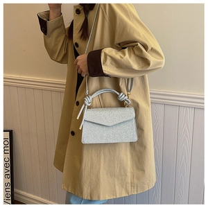 Silver glitter crossbody bag featuring a knotted handle and sleek rectangular flap design