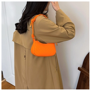 Dettaglio di una borsa a spalla arancione vivace con trapuntatura a V e cinturino annodato