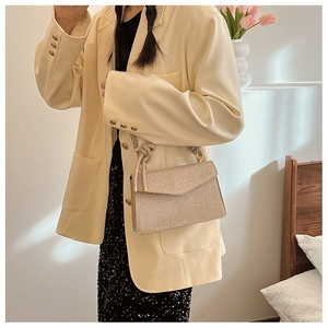 Detail of champagne gold sequined handbag with unique braided knot shoulder strap design
