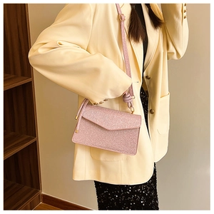Pink sequin crossbody bag with unique knot shoulder strap detail worn with a stylish outfit