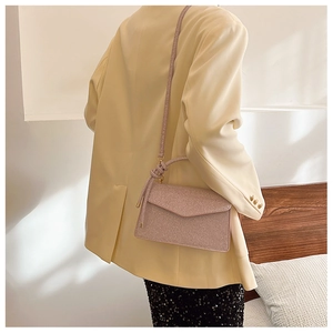 Detail of glitter crossbody bag on model with lavender metallic finish and sleek strap