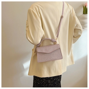 Close-up of stylish glitter crossbody bag in light purple with knotted handle detail