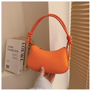 Dettaglio borsa baguette arancione acceso in pelle PU con trapuntatura a V e manico a nodo