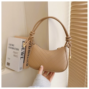 Dettaglio della borsa a mezzaluna trapuntata beige con cinturino annodato e hardware dorato