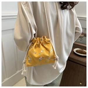Detail of yellow canvas bucket bag with floral embroidery and cotton drawstring strap