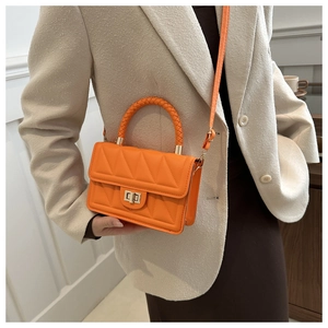 Orange geometric quilted handbag with woven handle and metal lock shown on a model