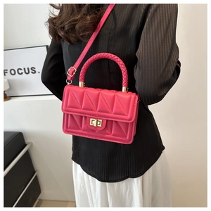 Detail of rose pink quilted crossbody bag with woven handle and gold metal twist lock