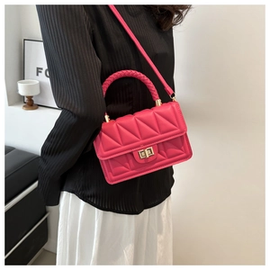 Close-up of rose red quilted handbag with golden twist lock and woven handle detail