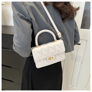Detail of white quilted PU leather handbag with woven handle and gold twist lock
