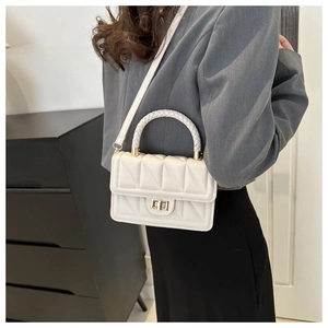 Close-up of white quilted handbag with woven handle and gold-tone twist lock detail