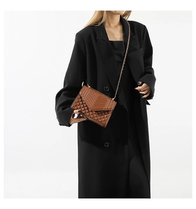 Détail du sac à chaîne en cuir matelassé porté avec une veste de blazer noire