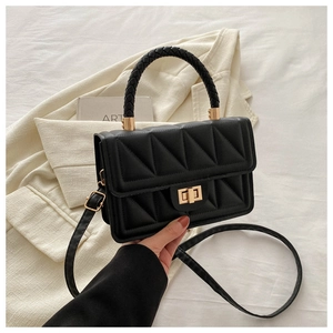 Detail of black quilted crossbody bag with gold rotating lock and woven handle texture