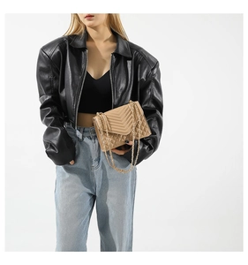 Détail du sac matelassé beige avec surpiqûres en V et bandoulière en chaîne dorée cuir