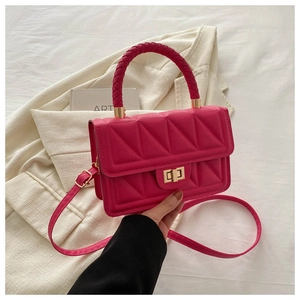 Detail of fuchsia quilted square handbag with gold twist lock and woven top handle