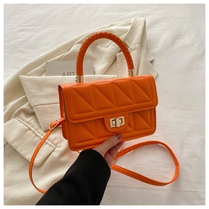 Close-up of orange quilted PU leather bag with woven handle and gold twist lock