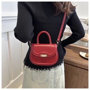 Detail of red half-moon leather handbag with golden spiral lock on a female model