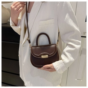 Detail view of a vintage dark brown saddle bag with a golden metal twist lock closure