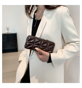 Vue macro d'une pochette en cuir verni marron foncé avec gaufrage géométrique