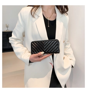 Close-up of black glossy quilted leather long wallet with elegant V-pattern stitching