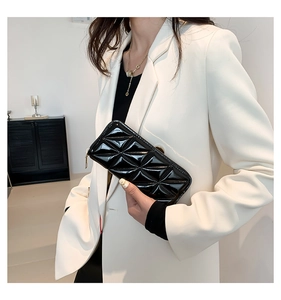 Detail of glossy black quilted long wallet with gold zipper held by a model