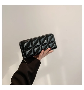 Détail d'une pochette noire vernie à motif géométrique et fermeture éclair dorée