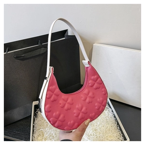 Detail of pink half-moon underarm bag featuring embossed clover texture and white strap