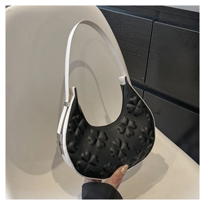 Detail of hobo bag featuring embossed clover patterns and black and white contrast design