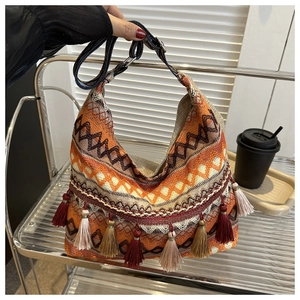 Détail du sac cabas tissé bohème avec motifs géométriques et pompons multicolores