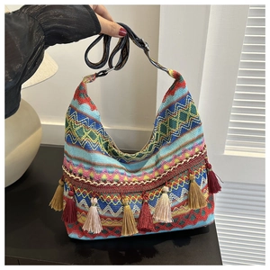 Détail d'un sac bohème tissé avec des motifs de vagues géométriques et de longs pompons colorés