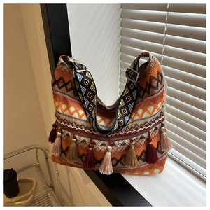 Détail d'un sac cabas tissé bohème avec des motifs géométriques et glands décoratifs