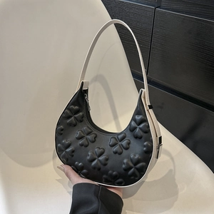Chic black and white crescent underarm bag with embossed clover pattern and silver zipper