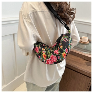 Detailansicht einer halbmondförmigen Umhängetasche mit buntem Blumenmuster und breitem Gurt
