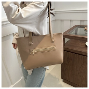 Vista laterale di una borsa tote kaki indossata da una modella in un interno domestico moderno