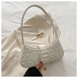 Détail du sac baguette matelassé crème avec coutures géométriques et boucle carrée élégante