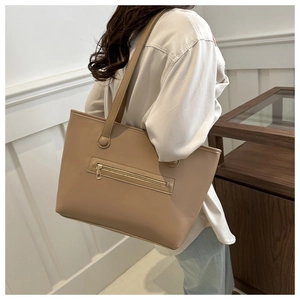Vista laterale della borsa tote grande in pelle beige con cerniera indossata da modella