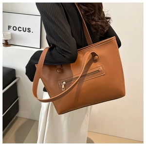 Dettaglio della borsa tote in ecopelle marrone con tasca esterna a zip dorata e doppie tracolle