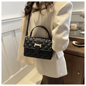 Detail view of black quilted leather shoulder bag with golden H-clasp and elegant texture