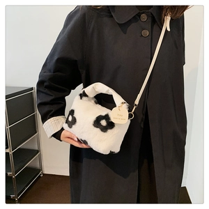 Détail d'un sac bandoulière en peluche blanche à fleurs noires avec anse en cuir