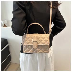 Detailed view of quilted beige crossbody bag with gold buckle on a stylish model