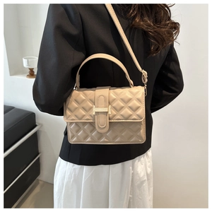 Detail of light apricot quilted crossbody bag with golden H-shaped clasp and metal hardware