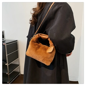 Vue détaillée du sac bandoulière en peluche marron avec poignées en cuir et texture douce