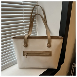 Dettaglio di una borsa tote bicolore con tasca con zip kaki su una superficie bianca