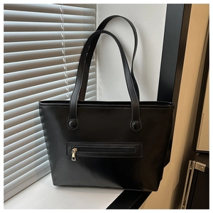 Dettaglio della borsa tote minimalista in pelle sintetica nera con cerniera dorata lucida