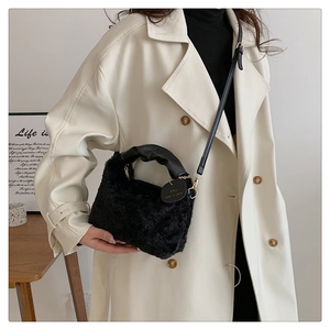Détail du sac à main en peluche noire avec poignée froncée et pendentif en forme de cœur