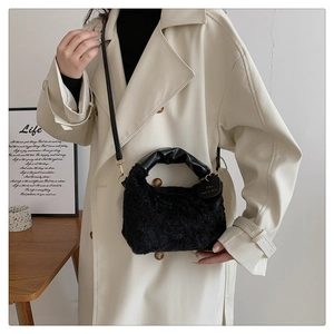 Détail du sac à main en peluche noire avec poignée en cuir plissée et breloque chic